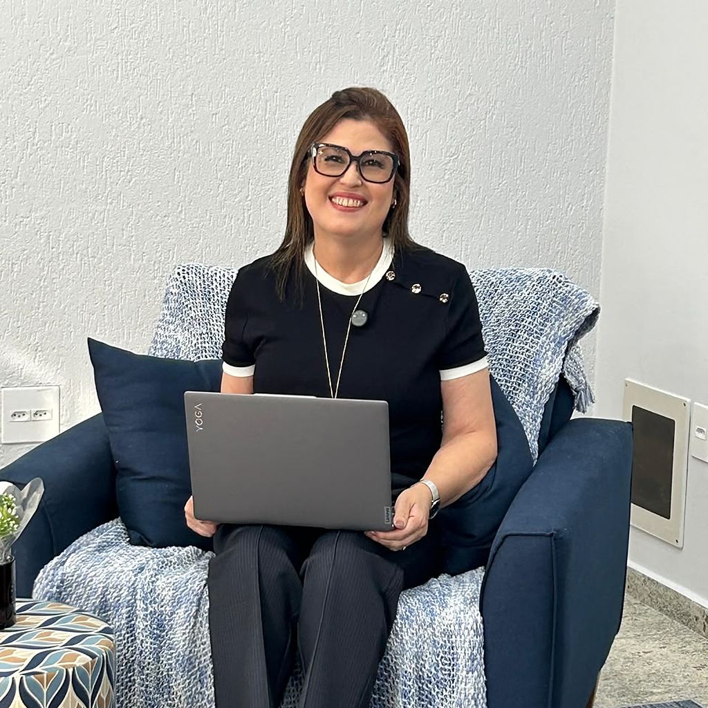 Nirã Valentim, psicóloga há 30 anos, sentada em poltrona com notebook no Espaço TeSer