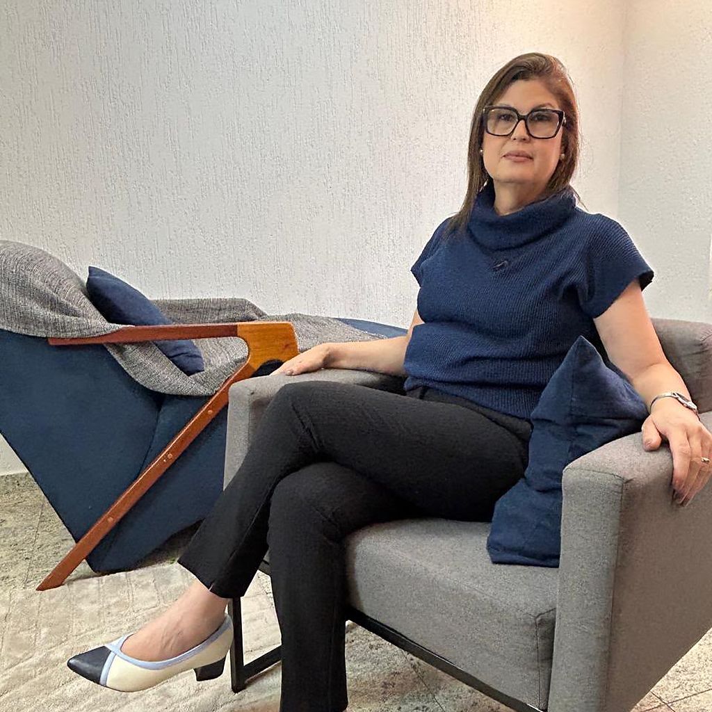 Nirã Valentim, mestre e doutora em Psicologia Clínica pela USP, sentada em poltrona no consultório